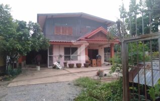 หน้าบ้าน ถ่ายจากประตูรั้วบ้าน มีที่จอดรถ และลานกว้าง